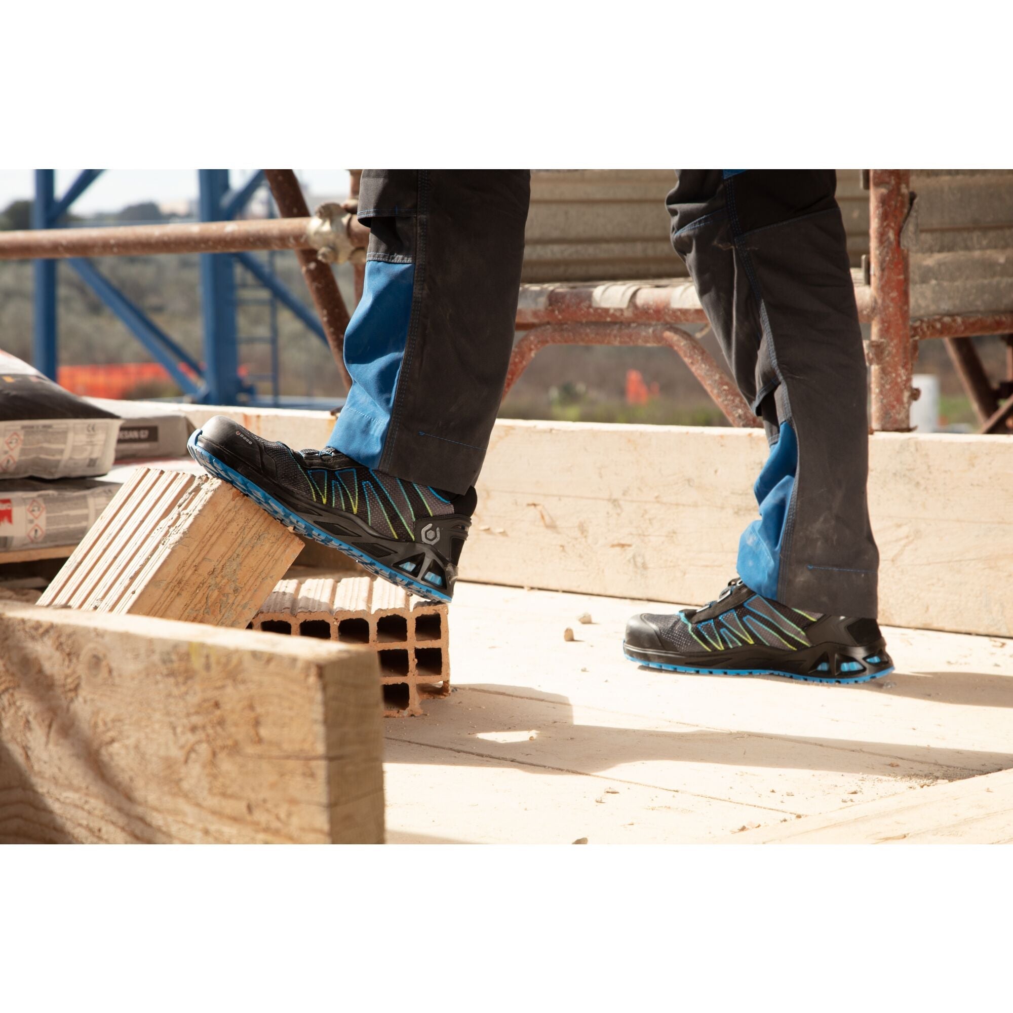 Worker wearing safety shoes stepping onto a wooden surface at a job site