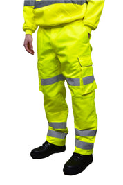 A person wearing high-visibility yellow work trousers with reflective grey stripes around the knees, shins, and thighs. The pants have a cargo pocket on the side and are paired with black safety boots. Only the lower half of the person is visible. The trousers appear to be part of a workwear or safety uniform. by MAK Boots & Garments