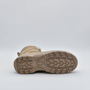 A single tan tactical boot shown from a rear three-quarter view, highlighting its textured rubber outsole tread against a light gray studio background.