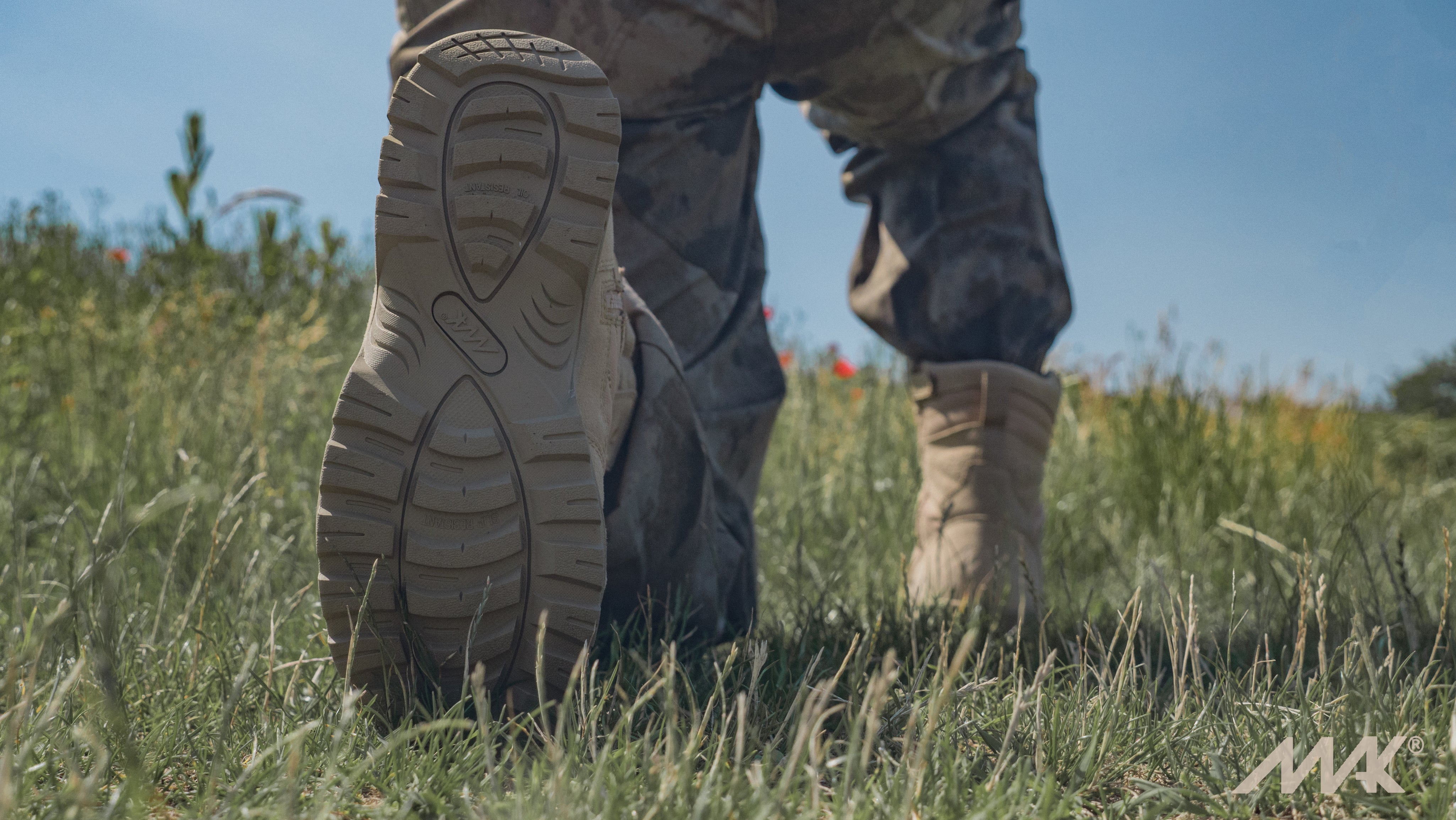 kneeling in the grass wearing the mak desert tan 9" protector tactical boot